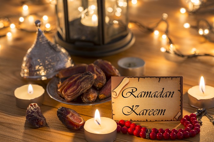 Greeting card Ramadan Kareem with dates, rosary, candles in brown wooden table