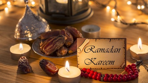 Greeting card Ramadan Kareem with dates, rosary, candles in brown wooden table