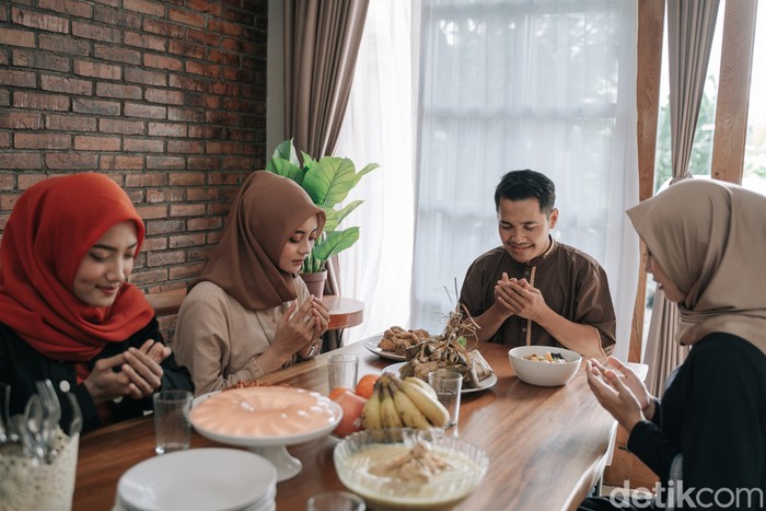 asian muslim people praying before having their food in dining room together for break fasting