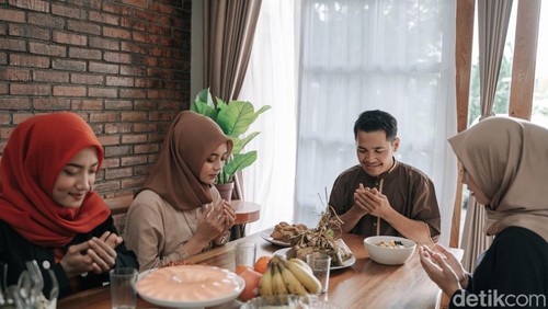asian muslim people praying before having their food in dining room together for break fasting