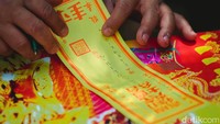 Keluarga tengah melipat kimce (duit perak) sebelum dibakar.