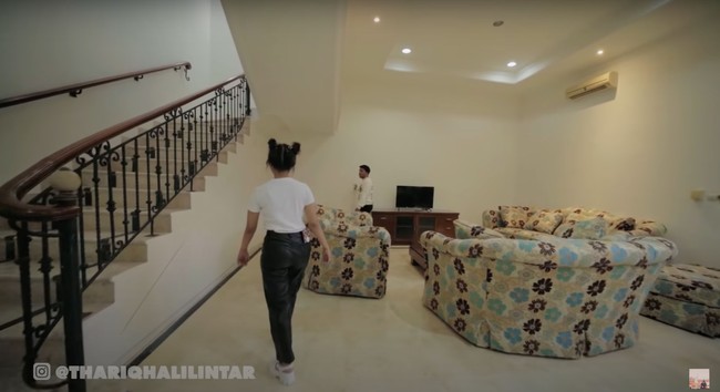 Masuk ke ruang tengah, beginilah penampakan ruang keluarga di rumah baru milik Thariq. Ruang keluarga tersebut terletak di sebelah tangga. Di bagian bawah tangganya sendiri terdapat sebuah lemari penyimpanan. Foto: dok. YouTube/Thariq Halilintar