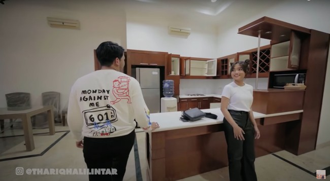 Tak jauh dari ruang keluarga, terdapat dapur dan ruang makan. Dapur tersebut terlihat sudah dilengkapi dengan kulkas, lemari, dan kitchen set berwarna coklat. Tak hanya itu saja, di setiap sudut ruangannya pun sudah terpasang AC. Foto: dok. YouTube/Thariq Halilintar