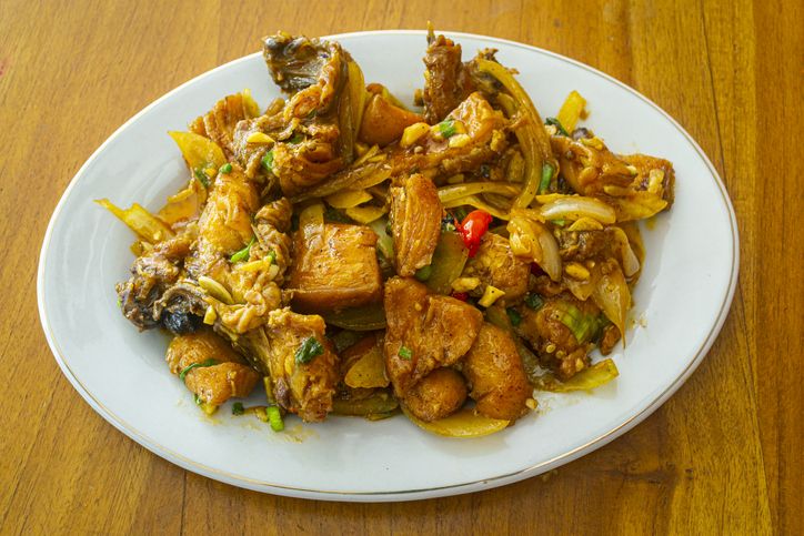 Delicious fried chicken butter in Indonesia called ayam goreng mentega, in white plate on wooden background