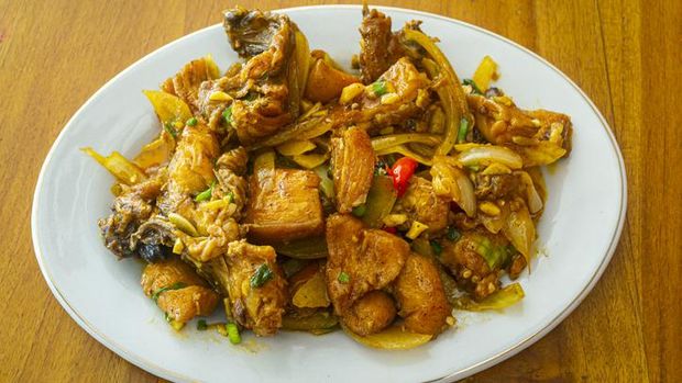 Delicious fried chicken butter in Indonesia called ayam goreng mentega, in white plate on wooden background