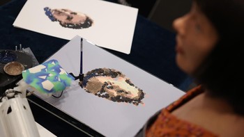 Ai-Da, seniman robot humanoid ultra-realistis, menunjukkan kemampuan melukisnya di hadapan media selama konferensi pers di The British Library pada 4 April 2022 di London, Inggris.