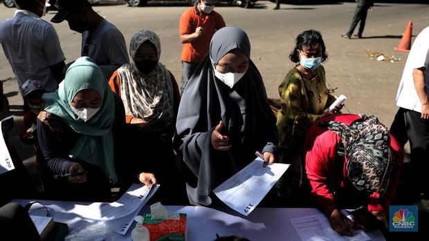 Petugas menyuntikkan vaksin Covid-19 dosis ketiga (booster) di Lobby Pasar Induk Kramat Jati, Jakarta, Rabu, 6 April 2022. (CNBC Indonesia/Muhammad Sabki)