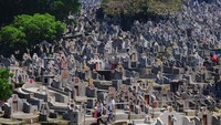 Orang-orang yang memakai masker berjalan di pemakaman selama Chinese Ching Ming, atau Hari Sapu Makam, di Hong Kong Selasa, (5/4/2022). Ribuan warga Hong Kong memberikan penghormatan kepada leluhur dan kerabat mereka selama festival tahunan.
