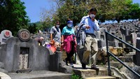 Sebuah keluarga berjalan melalui kuburan yang padat di pemakaman selama Chinese Ching Ming, atau Hari Pembersihan Makam. Tetap dilakukan di tengah wabah Covid-19 yang masih menghantui kota itu.