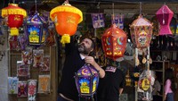 Seorang pria menggantung lentera tradisional untuk bulan suci Ramadhan di tokonya di Lebanon.