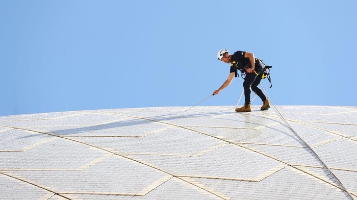1389607757 SYDNEY, AUSTRALIA - APRIL 05: Building Operations staff inspect tiles on the Sydney Opera House sails on April 05, 2022 in Sydney, Australia. The 'tile tapping' test is conducted every five years to inspect the health of the tiles that cover the Sydney Opera Houses' iconic sails and takes six weeks to complete. A specific type of hammer is used to lightly tap the tiles with each tile emitting a particular type of sound which indicates whether it is due for repair or still in good condition. There is a limited supply of backup tiles in stock for replacement, so the tile tapping check is an essential maintenance activity for the building. (Photo by Mark Metcalfe/Getty Images)