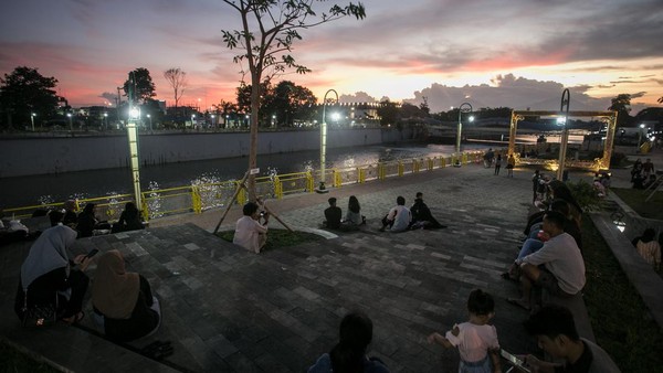 Warga duduk menikmati matahari terbenam di Taman Bendung Tirtonadi, Solo, Jawa Tengah, Rabu (6/4/2022).