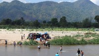Para pengungsi ini harus menyeberangi perbatasan untuk mengumpulkan makanan yang disumbangkan dan air kemasan. Lalu membawanya kembali ke sisi sungai.