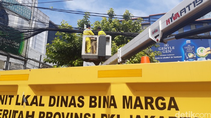 Pasukan kuning dari Dinas Bina Marga DKI Jakarta memotong kabel semrawut di Jl Mampang Prapatan Raya, Jakarta Selatan, 7 April 2022. (Danu Damarjati/detikcom)