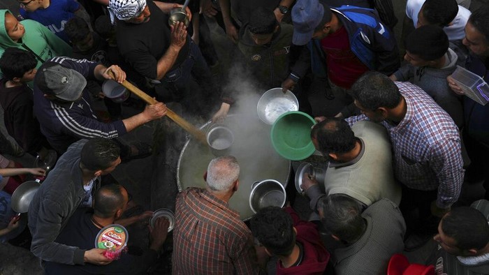 Semangkuk Sup Hangat untuk Berbuka dari Gang Sempit di Palestina People gather to receive hot wheat soup and porridge before they break their fast at sunset during the Muslim holy fasting month of Ramadan at the Shijaiyah neighborhood in Gaza City, Wednesday, April 6, 2022. (AP Photo/Adel Hana)