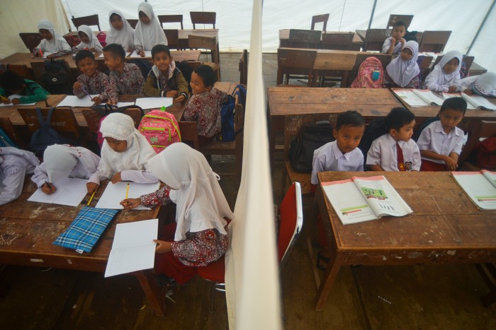 Sejumlah siswa mengikuti kegiatan belajar mengajar tatap muka di dalam tenda darurat di SDN 21 Kecamatan Pasaman, Nagari Aua Kuniang, Kabupaten Pasaman Barat, Sumatera Barat, Kamis (7/4/2022). Proses belajar mengajar (PBM) tingkat SD dan SMP di kabupaten yang terdampak gempa magnitudo 6,1 pada Februari lalu itu kini kembali dibuka selama Ramadhan, namun sebagian siswa terpaksa belajar di bawah tenda darurat karena bangunan sekolah mereka rusak. ANTARA FOTO/Iggoy el Fitra/wsj.
