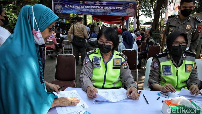 Petugas kesehatan dari kepolisiam memberikan vaksin booster kepada warga di kawasan Pasar Induk Kramat Jati,  Rabu (6/4).
