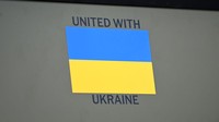 Kata-kata Bersatu dengan Ukraina juga terpampang dalam bahasa Inggris sebagai tanda solidaritas.