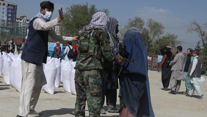 An Afghan girl waits to receive a rice sack, as part of humanitarian aid sent by China to Afghanistan, at a distribution centre in Kabul, Afghanistan, April 7, 2022. REUTERS/Ali Khara     TPX IMAGES OF THE DAY