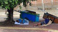 Beberapa warga beristirahat di bawah pohon agar lebih sejuk dan terhindar dari sengatan matahari.