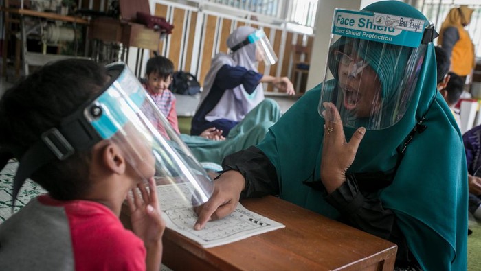 Kala Siswa Tuna Rungu Perdalam Ilmu Agama di Pesantren Kilat Guru mengajari siswa penyandang tuna rungu membaca Iqra dengan metode membaca gerak bibir saat mengikuti kegiatan Pesantren Kilat Ramadhan Tuna Rungu di SLB B Prawestri, Karanganyar, Jawa Tengah, Kamis (7/4/2022). Kegiatan yang dilaksanakan setiap bulan Ramadhan tersebut untuk mengajari siswa penyandang tuna rungu pengetahuan agama, tata cara shalat, membaca Iqra hingga Al Quran dengan metode gerak bibir dan merasakan getaran pita suara. ANTARA FOTO/Mohammad Ayudha/wsj.