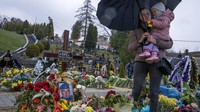 Seorang ibu dan anak mengunjungi makam suaminya yang seorang tentara setelah dia terbunuh dalam perang. (AP Photo/Nariman El-Mofty)