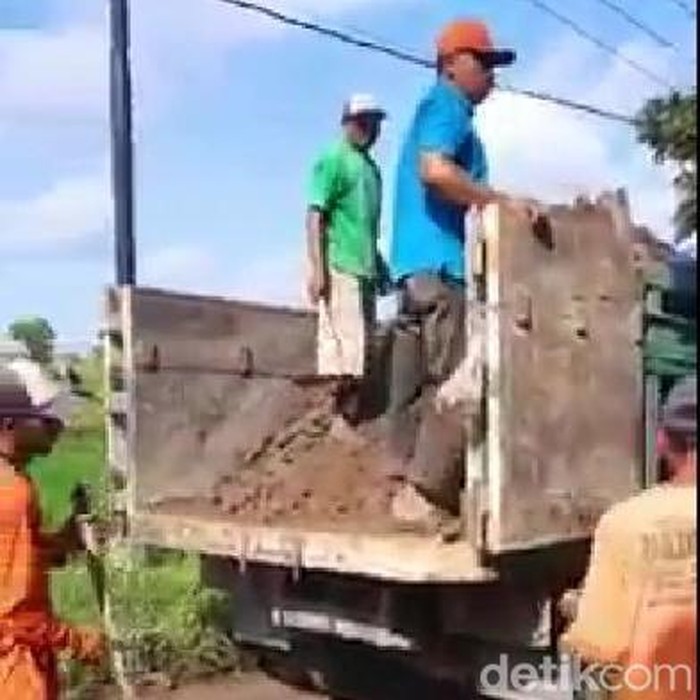 Para sopir truk urunan untuk menguruk jalan rusak