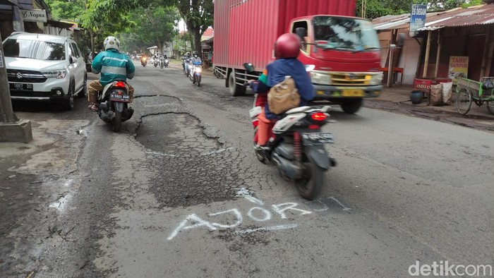 Ragam coretan dengan cat putih di jalan berlubang di Kota Malang.
