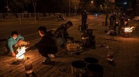 Seorang pria membakar uang kertas palsu di sebuah jalan di Beijing, China, Selasa (5/4/2022) waktu setempat.  