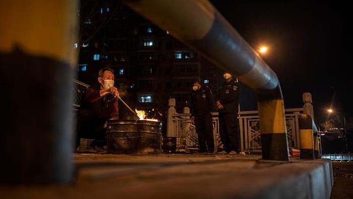 BEIJING, CHINA - APRIL 05: A woman burns fake paper money as an offering as part of a ceremony for a recently deceased relative on a street during the Qingming Festival on April 5, 2022 in Beijing, China. The Qingming festival, or Tomb-Sweeping Day, is an annual Chinese ritual to remember and honour one's ancestors and pay a visit to their graves, and is marked across the country. (Photo by Kevin Frayer/Getty Images)