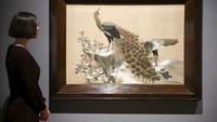 Seorang karyawan galeri berpose di depan panel bordir Jepang yang diberikan kepada King George V pada 1935.   