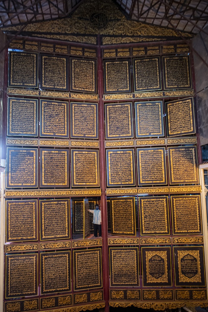 Megahnya Al-Qur'an Raksasa di Palembang Berukir Tinta Emas Pengunjung membaca ayat-ayat suci yang ada di Al Quran Al-Akbar di Palembang, Sumatera Selatan, Sabtu (9/4/2022). Keberadaan Al Quran raksasa yang diukir di atas kayu trembesi itu menjadi destinasi wisata religi di Kota Palembang selama bulan suci Ramadhan. ANTARA FOTO/Nova Wahyudi/wsj.