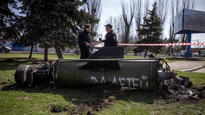 Ukrainian police inspect the remains of a large rocket with the words 
