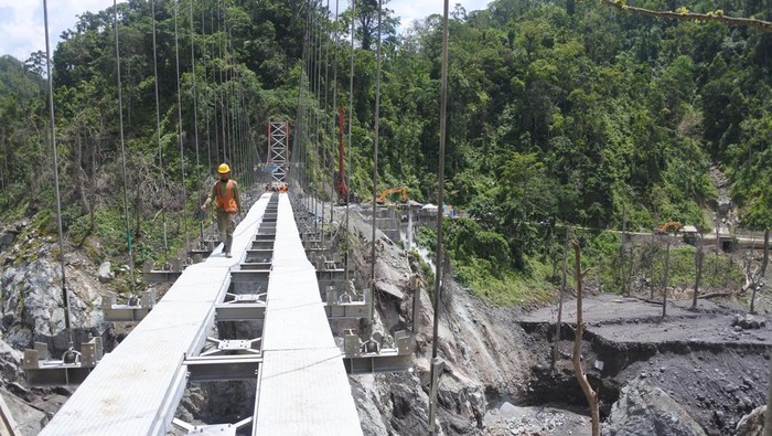 Sejumlah pekerja menyelesaikan pembangunan jembatan gantung Gladak Perak di Lumajang, Jawa Timur, Sabtu (9/4/2022). Kementerian Pekerjaan Umum dan Perumahan Rakyat membangun jembatan gantung darurat tersebut untuk dilewati sementara oleh kendaraan roda dua, sebelum jembatan permanen yang rusak akibat awan panas guguran Gunung Semeru kembali dibangun. ANTARA FOTO/Seno/wsj.