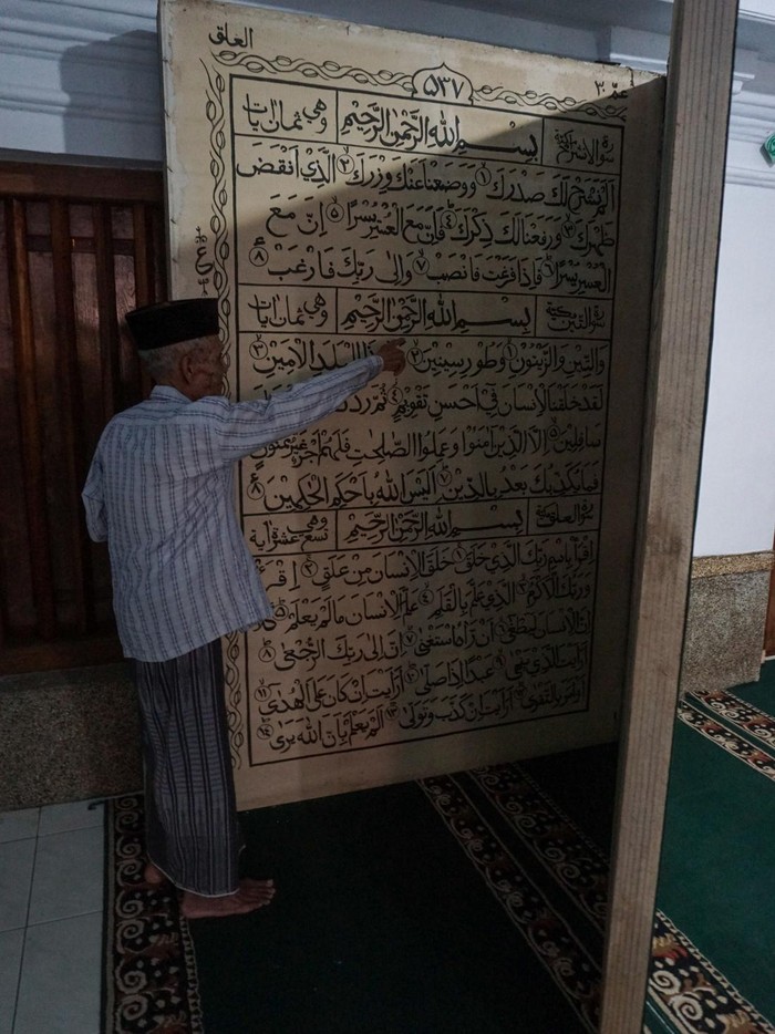 Seorang pengurus masjid menunjukkan replika Al Quran berukuran besar di Masjid Jami Aulia, Sapuro, Pekalongan, Jawa Tengah, Sabtu (9/4/2022). Menurut Ketua Umum Yayasan Masjid Jami Aulia Sapuro KH Ahmad Dananir Dananjoyo, replika Al Quran dari bahan tripleks berukuran panjang 2,3 meter dan lebar dua meter itu ditulis secara manual oleh seorang warga Pekalongan bernama Rahmat yang berisi sebagian ayat dari Juz 30. ANTARA FOTO/Harviyan Perdana Putra/wsj.