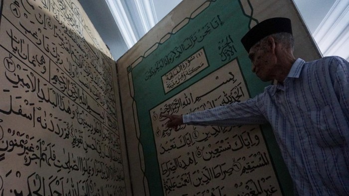Seorang pengurus masjid menunjukkan replika Al Quran berukuran besar di Masjid Jami Aulia, Sapuro, Pekalongan, Jawa Tengah, Sabtu (9/4/2022). Menurut Ketua Umum Yayasan Masjid Jami Aulia Sapuro KH Ahmad Dananir Dananjoyo, replika Al Quran dari bahan tripleks berukuran panjang 2,3 meter dan lebar dua meter itu ditulis secara manual oleh seorang warga Pekalongan bernama Rahmat yang berisi sebagian ayat dari Juz 30. ANTARA FOTO/Harviyan Perdana Putra/wsj.