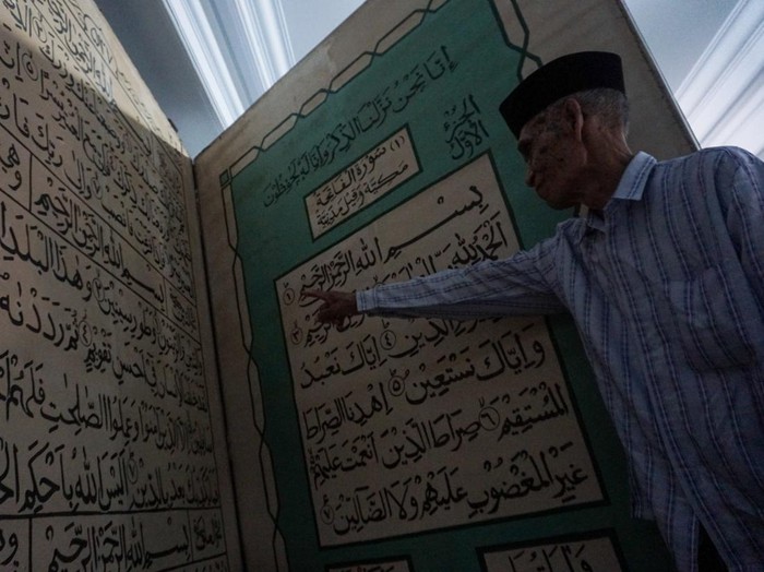 Seorang pengurus masjid menunjukkan replika Al Quran berukuran besar di Masjid Jami Aulia, Sapuro, Pekalongan, Jawa Tengah, Sabtu (9/4/2022). Menurut Ketua Umum Yayasan Masjid Jami Aulia Sapuro KH Ahmad Dananir Dananjoyo, replika Al Quran dari bahan tripleks berukuran panjang 2,3 meter dan lebar dua meter itu ditulis secara manual oleh seorang warga Pekalongan bernama Rahmat yang berisi sebagian ayat dari Juz 30. ANTARA FOTO/Harviyan Perdana Putra/wsj.