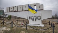 Bendera Ukraina berkibar di monumen dengan tanda bertuliskan Pripyat, nama kota, di kota ditinggalkan Pripyat dekat Pembangkit Listrik Tenaga Nuklir Chernobyl, Ukraina. AP/Oleksandr Ratushniak