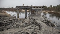Prajurit Ukraina berdiri di jembatan yang hancur antara desa Dytiatky dan Chernobyl, Ukraina. AP/Oleksandr Ratushniak