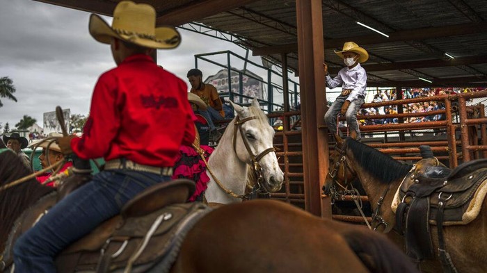 A cowboy wearing a mask as a precaution amid the spread of COVID-19 looks at other comrades during the competition at the Boyeros Cattlemen's fair rodeo during the International Agricultural Fair Fiagrop 2022 in Havana, Cuba, Friday, April 8, 2022. The rodeo in Cuba is a tradition over two centuries old. (AP Photo/Ramon Espinosa)