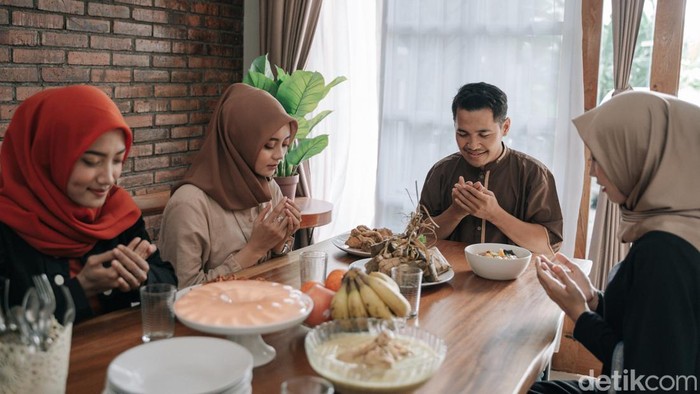 asian muslim people praying before having their food in dining room together for break fasting