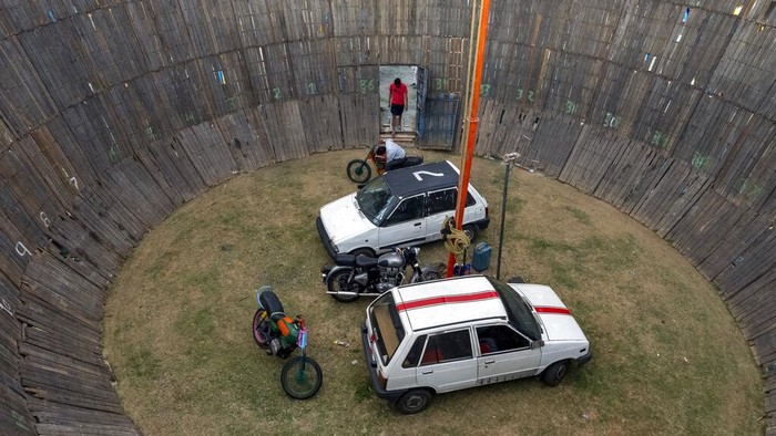 Pushpender, stands at the entrance of an enclosure known as Maut ka Kuan or the well of death at a local fair in Dharmsala, India, Saturday, April 9, 2022. Pushpender and others perform death defying stunts on motor bikes and cars for very little money at traditional fairs all over the country. (AP Photo/Ashwini Bhatia)