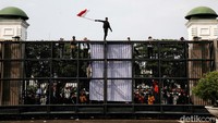 Mahasiswa memanjat gerbang Gedung DPR, Jakarta, untuk menyuarakan aspirasinya, Senin (11/4/2022). Mereka juga mengibarkan bendera merah putih dari atas gerbang.