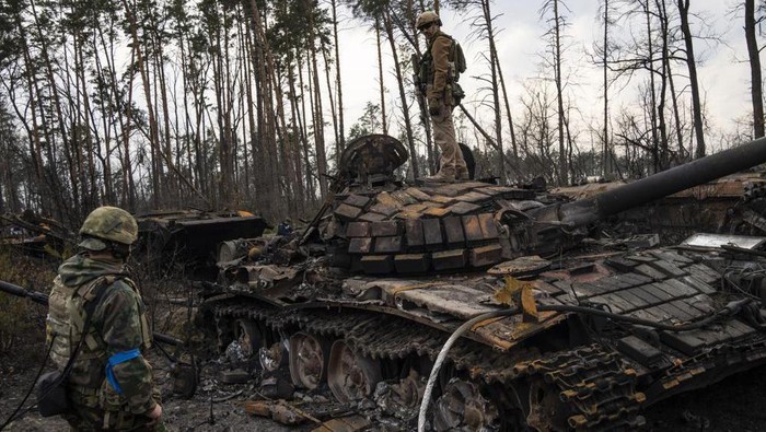 A Ukrainian soldier stands one top of a destroyed Russian tank on the outskirts of Kyiv, Ukraine, Thursday, March 31, 2022. (AP Photo/Rodrigo Abd)