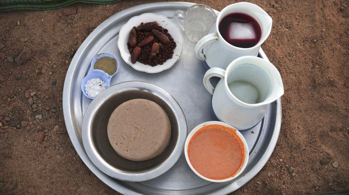 Warga Sudan Ramai-ramai Cegat Pengendara di Jalan, Ada Apa? A plate is filled with chickpeas and dates ready to be provided to observing Muslims to break their Ramadan fast along the side of the road of the Jazeera State highway in the village of al-Nuba, about 50 kilometers south of Sudan's capital, Khartoum, Friday, April 8, 2022. (AP Photo/Marwan Ali)
