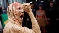 Seseorang memberi isyarat saat penduduk asli melakukan pertunjukan Ouro de Sangue (Blood Gold) di depan Kementerian Pertambangan dan Energi saat mereka mengambil bagian dalam pawai untuk memprotes Presiden Brasil Jair Bolsonaro. (Adriano Machado/Reuters)