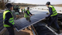 Pekerja memasang panel surya di pembangkit listrik fotovoltaik terapung di danau Silbersee (Danau Perak) di Haltern am See, Jerman, Senin, (11/4/2022). (Thilo Schmuelgen/Reuters)