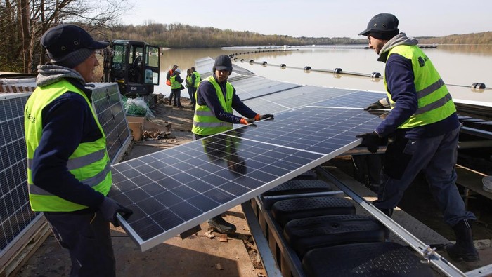 Jerman Bikin Pembangkit Listrik Tenaga Surya Terapung di Danau A boat pulls solar panels towards a floating photovoltaic power plant on lake Silbersee (Lake Silver) in Haltern am See, Germany, April 11, 2022. Picture taken with a drone. REUTERS/Erol Dogrudogan TPX IMAGES OF THE DAY