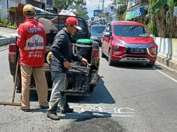 Petugas Pemkot Malang memperbaiki sejumlah jalan berlubang yang ditulisi warga.