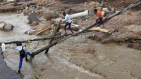Tak hanya merusak rumah, banjir juga menyebabkan jembatan di kawasan Ntuzuma hanyut. Kondisi itu membuat warga membangun jembatan darurat agar dapat menyeberangi sungai. (AP Photo/Str).  